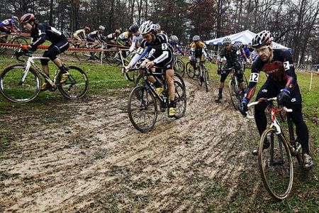 The men's elite field negotiates a slippery corner on the opening lap.