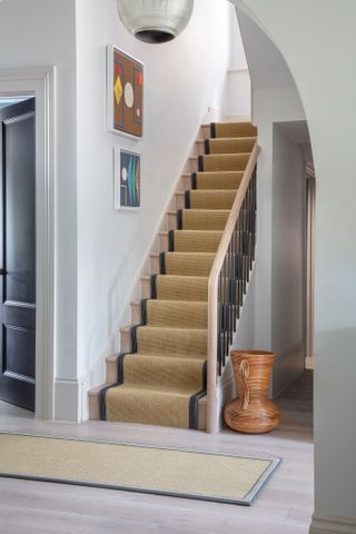 hallway with arched entrance, wooden flooring, sisal effect runner on floor and stairs