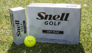 Snell Get Sum Golf Ball in front of Snell packaging and boxes