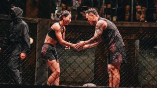 sim yu-ri and hunter lee shake hands while standing in an octagon, with a referee to their left, in 'physical 100' season 2