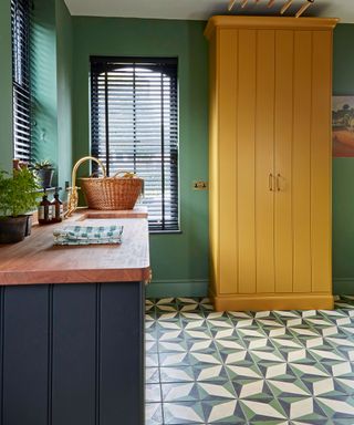 Colorful kitchen with yellow cabinet, green walls and geometric floor tiles