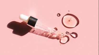 Flat lay. Liquid gel or serum drop with pipette on pink background in macro. - stock photo