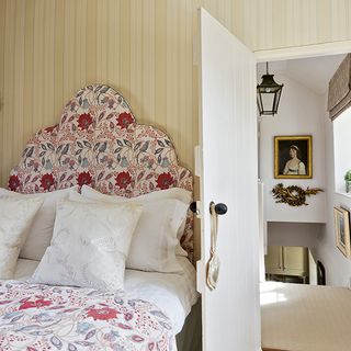 guest bedroom with yellow striped wallpaper and floral fabrics with white door