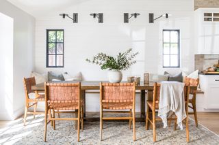 white farmhouse style dining room with shiplap walls, bench seating and leather and wood chairs, vintage rug