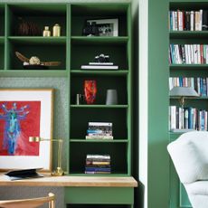 Desk area built in beside steps, green wallpapered wall and inbuilt green bookshelves