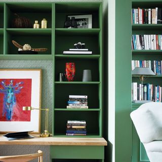 Desk area built in beside steps, green wallpapered wall and inbuilt green bookshelves
