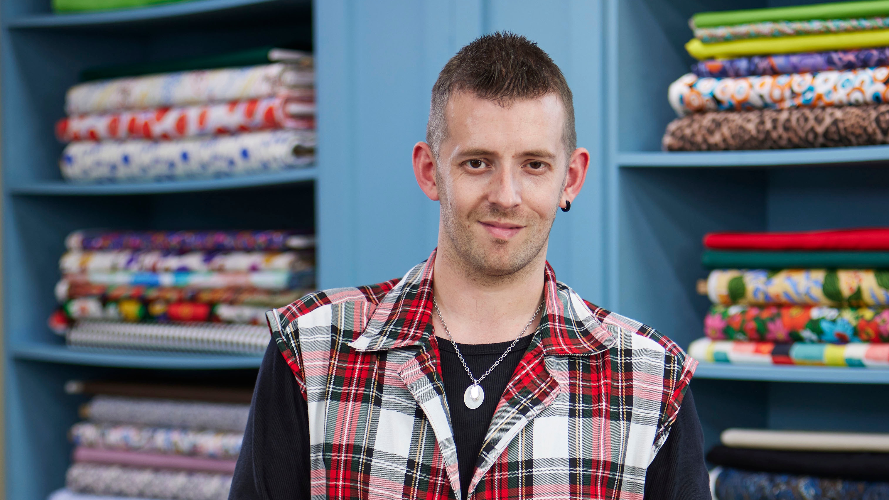 Dan standing in the Great British Sewing Bee studio and smiling for the camera