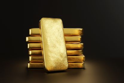 Gold bullion leaning on a stack of gold ingots.