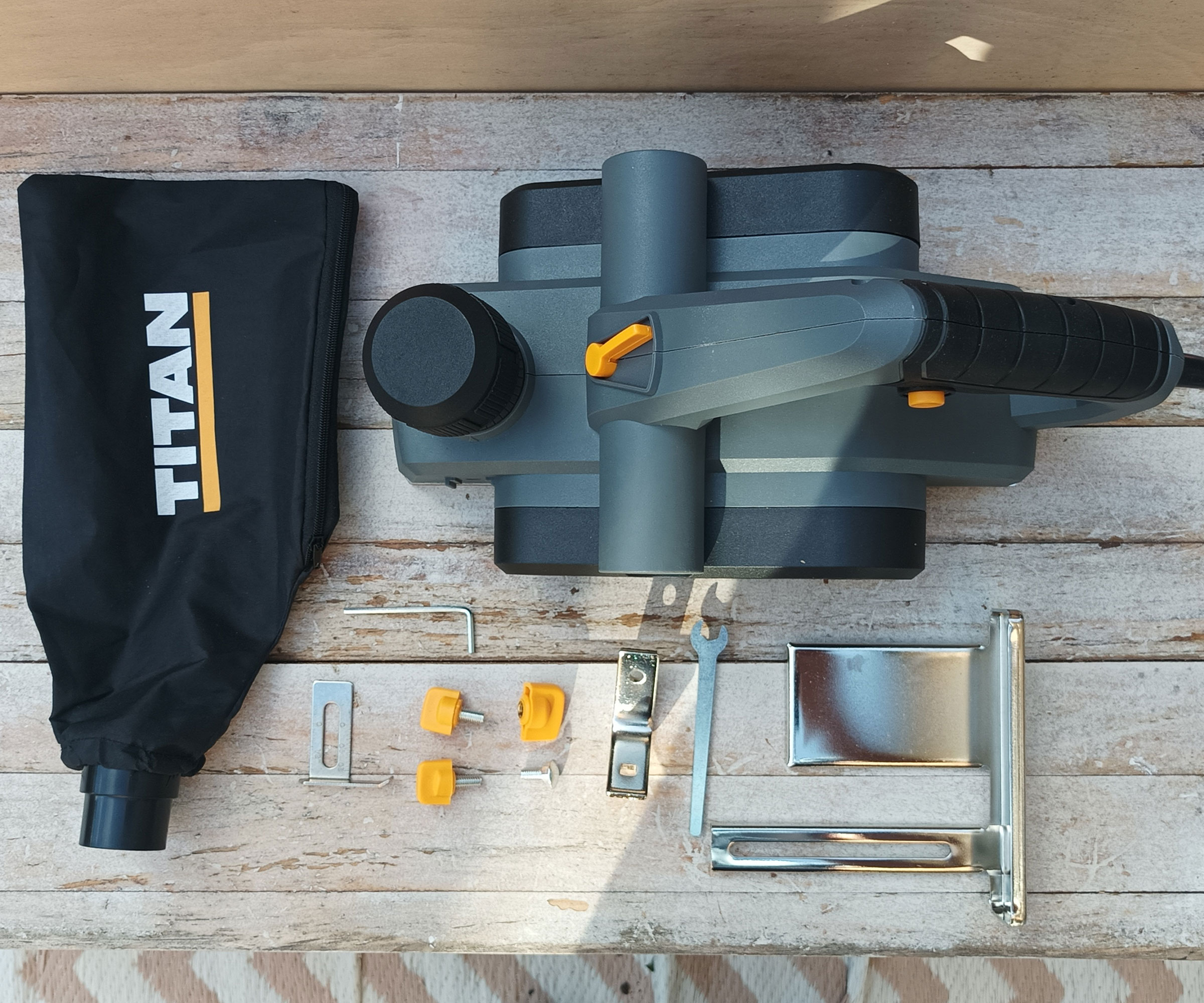 Top down shot of Titan TTB876PLN 3mm Electric Planer with accessories laid out on whitewashed wood background
