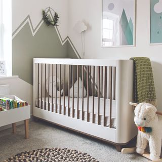 White cot, textured rug, painted mountain scenery on walls and sheep on floor