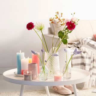 room with white wall and white table with red flower in glass vase
