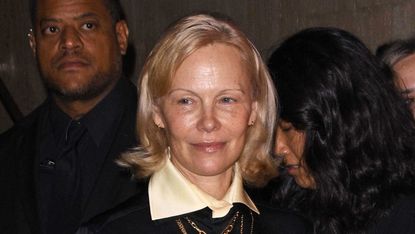 Pamela Anderson wearing a black outfit and gold medallions