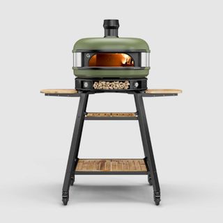 Green pizza oven on a fold out wooden table with wheels 
