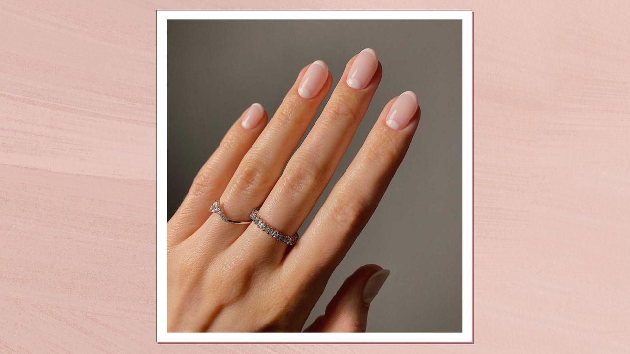 A hand wearing silver jewellery is pictured with almond nails and a pink pastel french tip manicure by nail artist @matejanova/Mateja Novakovic/ in a pink template