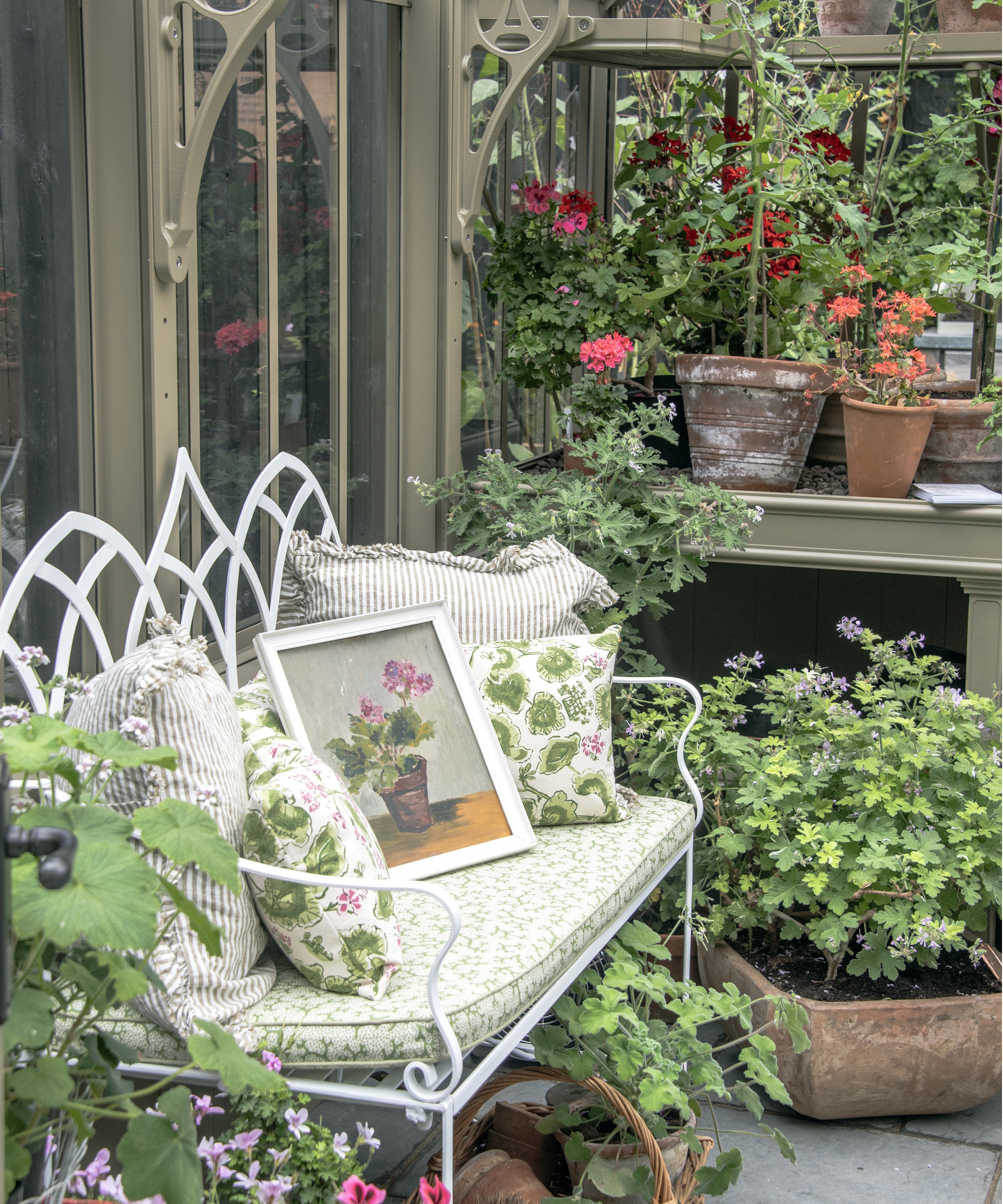 Glasshouse with bench next to lots of potted plants