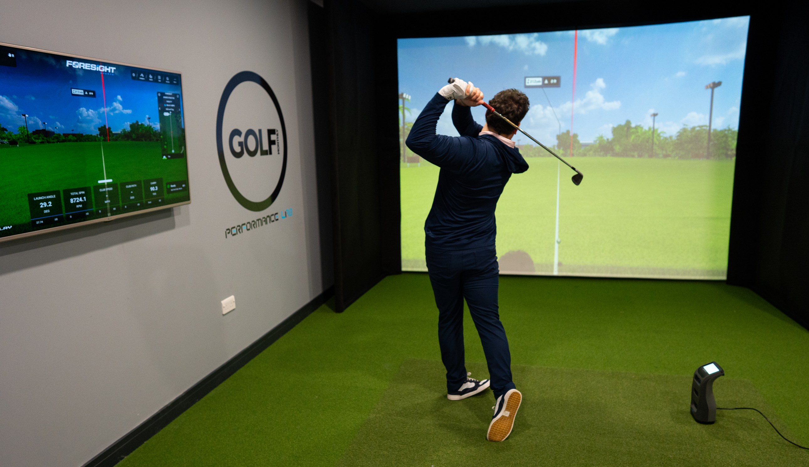 A golfer hits into a screen