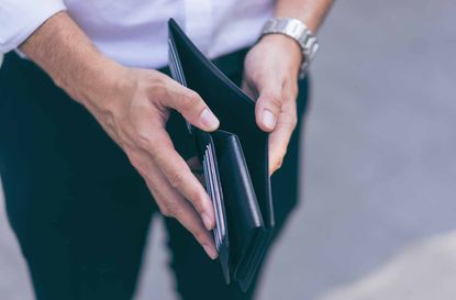 Man standing holding black wallet empty of money