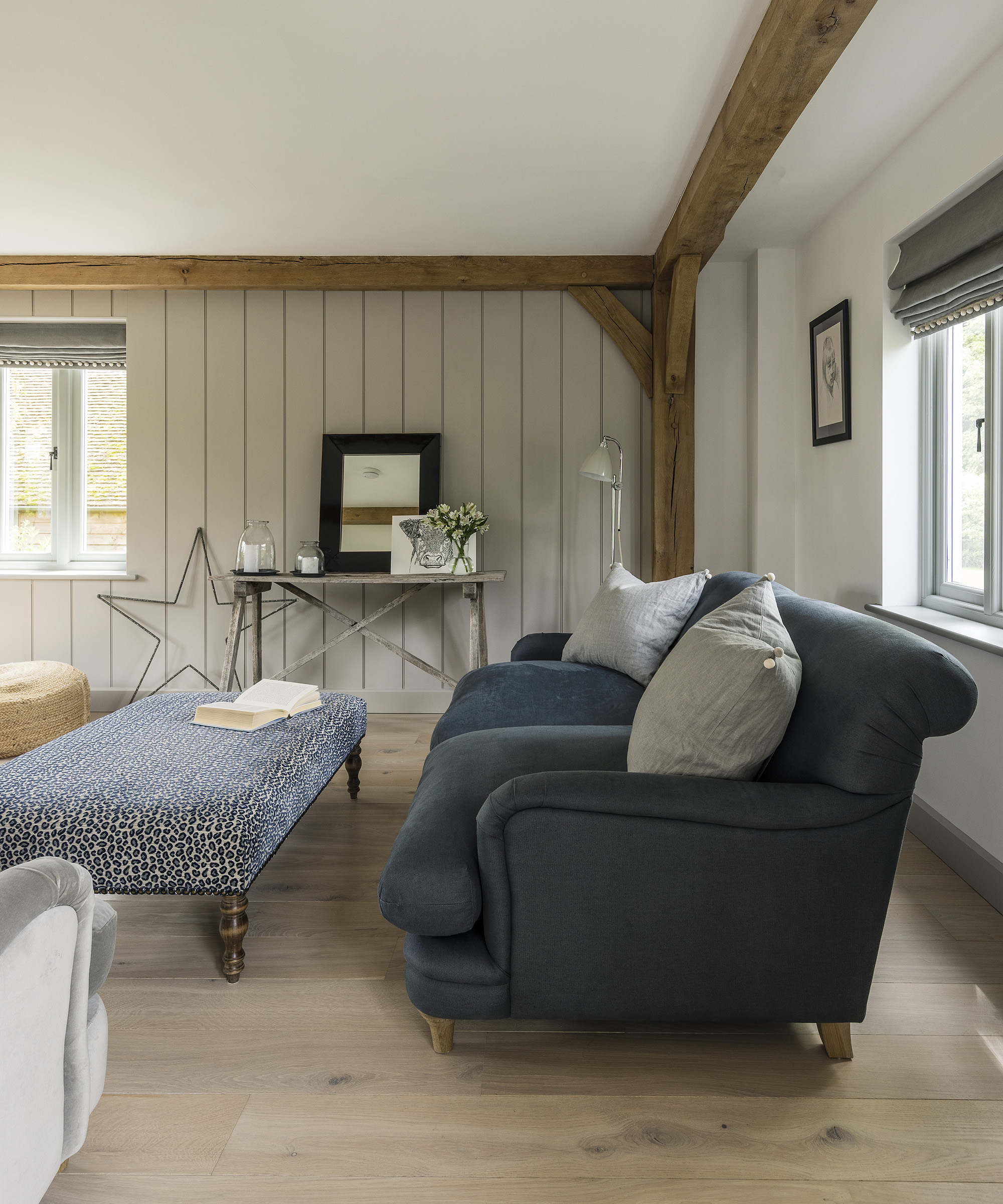 A cosy living room with light and neutral tones and large navy sofa giving a rustic yet modern feel