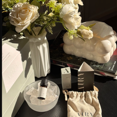 Airy crystal diffuser on a black table next to a vase of white roses.