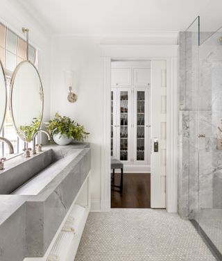 A white bathroom with grey marble and nickle fixtures