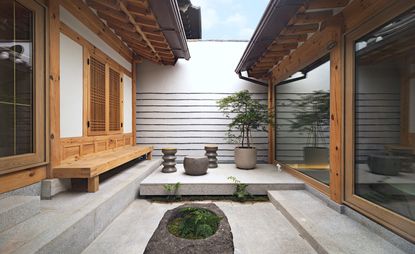 Renovated Seoul hanok courtyard with wooden bench and stone seating