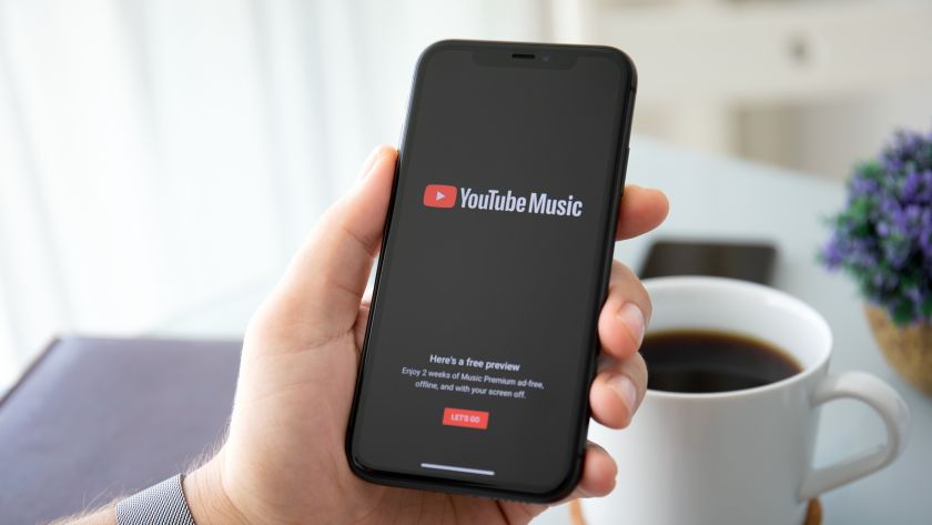 Man holding iPhone 11 with service YouTube Music Premium on the screen