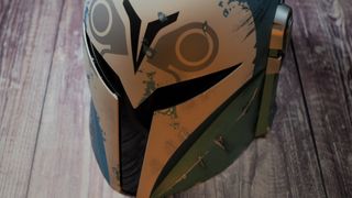 A top-down view of The Black Series Bo-Katan helmet as it sits on a wooden table
