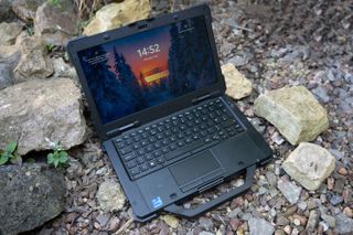 A black Dell Latitude 7330 Rugged Extreme laptop sitting on a rocky surface