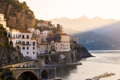 A view of the Amalfi Coast at sunset, with water and buildings tucked into cliffs.