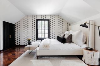 black and white bedroom with black and white wallpaper, black floor light, wooden floorboards, white bedding, white rug