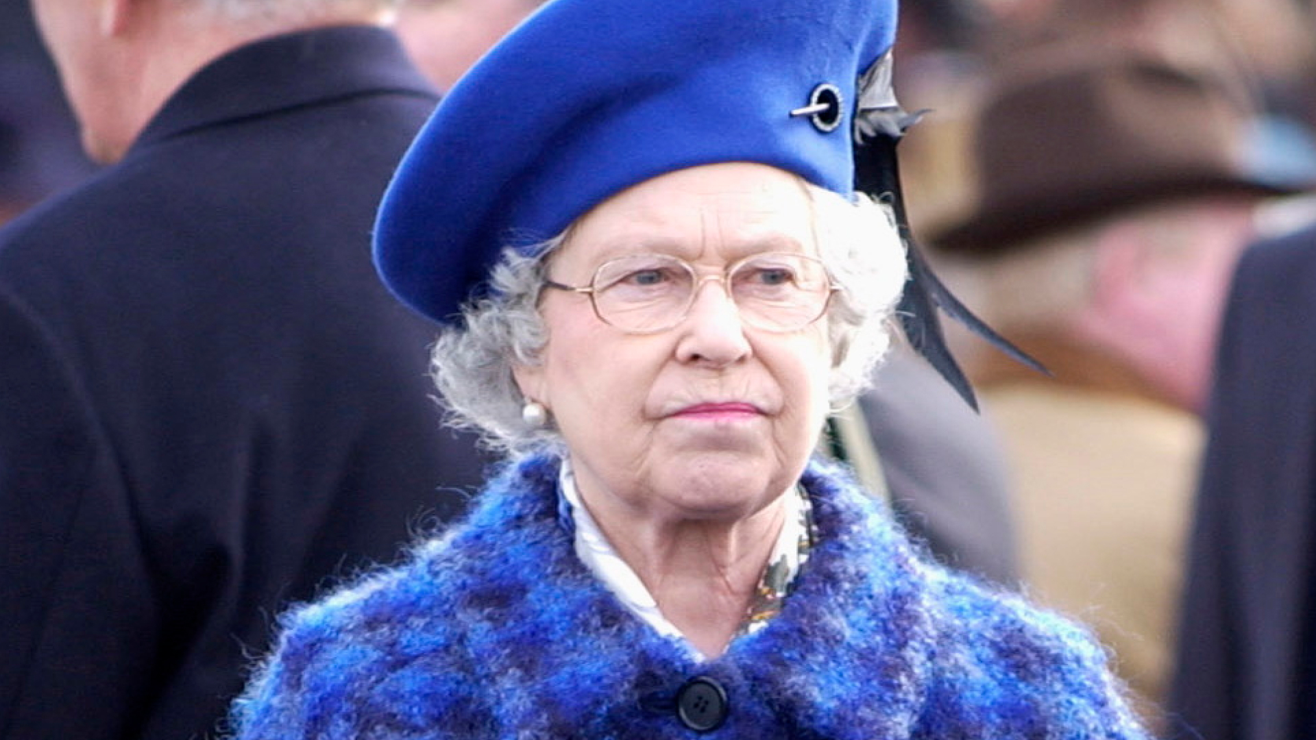 Queen Elizabeth Il Looking Serious Before The Race On Gold Cup Day At The Cheltenham National Hunt Festival While Wearing a Blue and Purple checkered coat and a royal blue hat