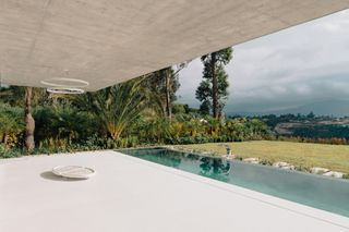 Magnolia House, Ecuador with a white covered pavement, outdoor pool, garden surrounded by trees.