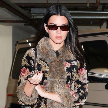 Kendall Jenner wearing a fur-trimmed jacket, dark-wash Khaite jeans, and black The Row ballet flats
