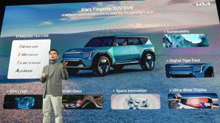 Kia CEO Ho Sung Song standing in front of a large screen showing EV9 specs