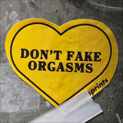 yellow heart-shaped sticker that says "Don't fake orgasms"