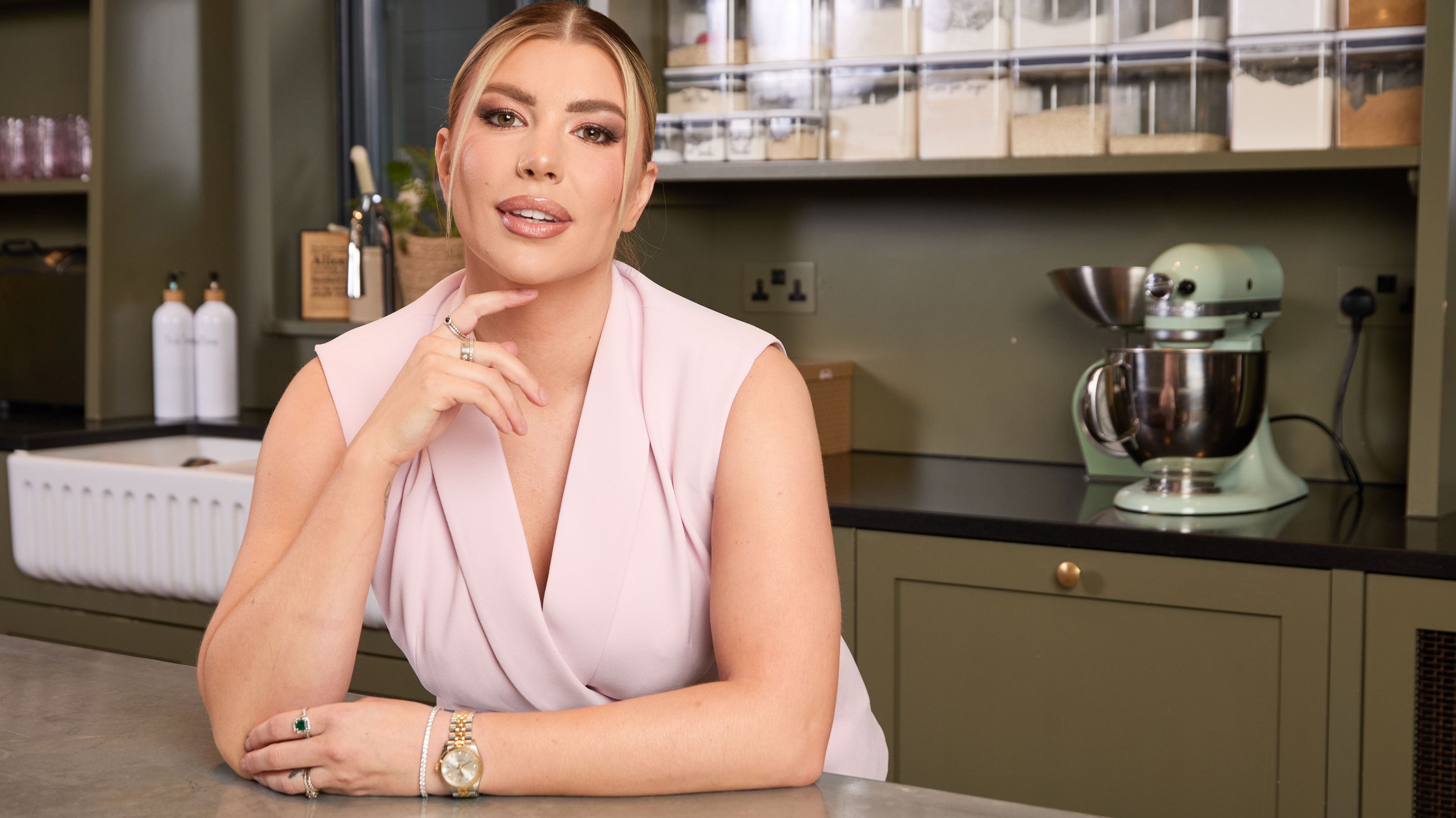Olivia Bowen in pink suit stood in a green kitchen