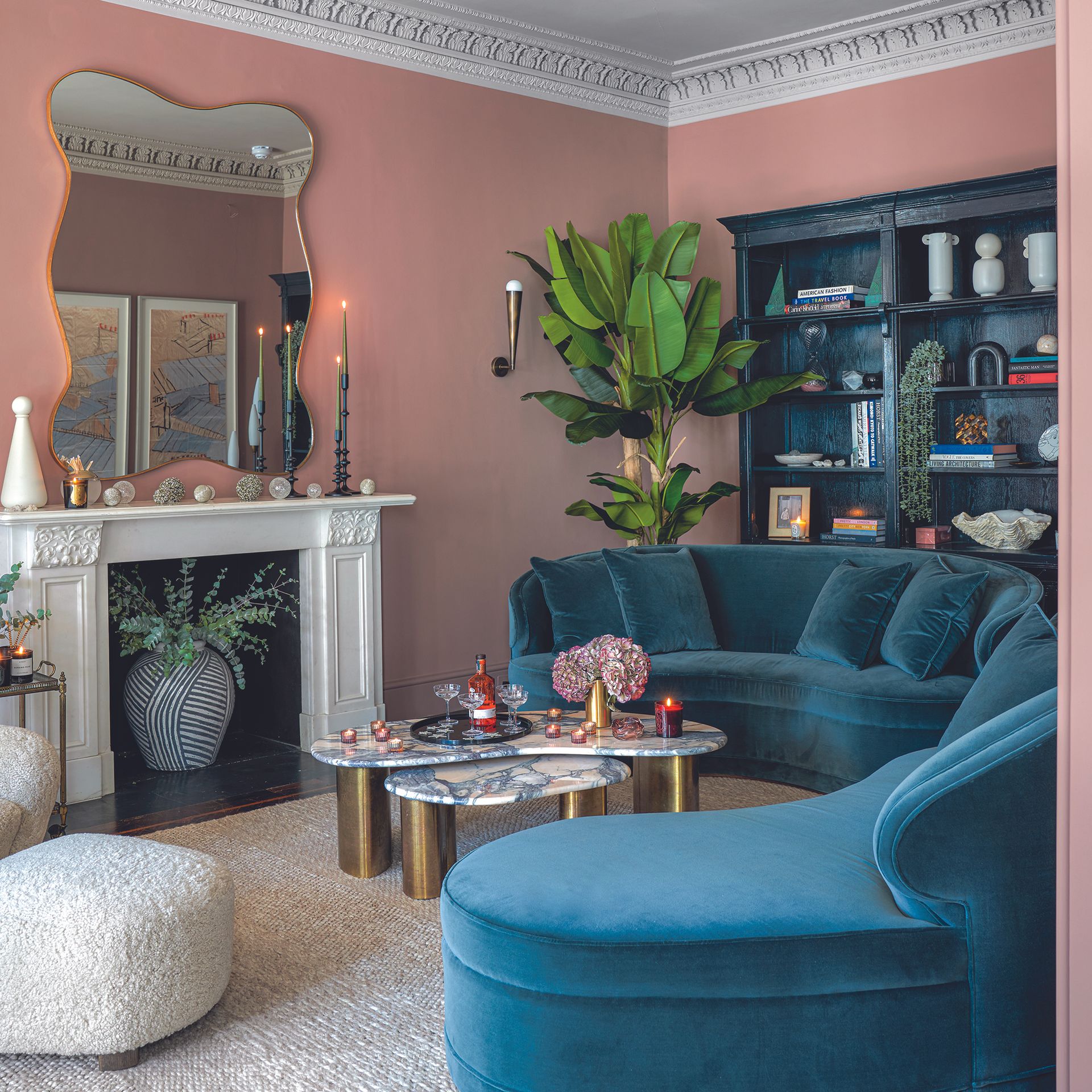 Living room with pink walls and teal sofa.