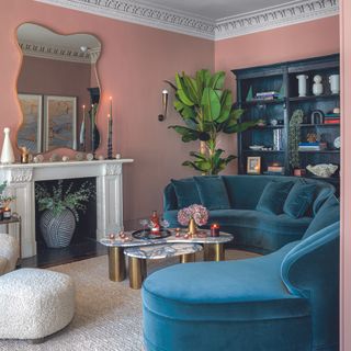 Living room with pink walls and teal sofa.