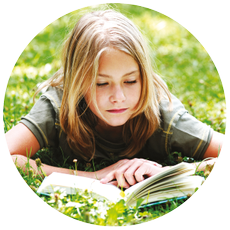 Image of young girl lying on the grass reading a book