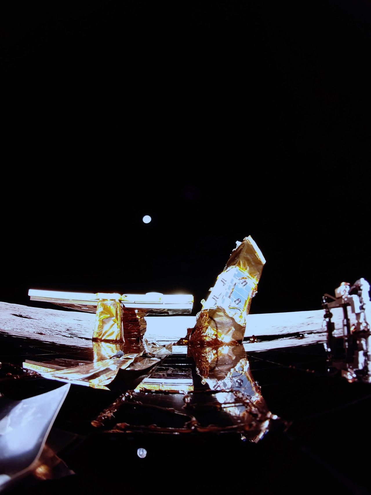 An image of the top deck of Blue Ghost's lunar lander on the surface of the moon with Earth in the background.