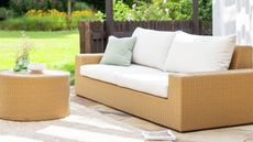 Image of a jute-effect outdoor sofa with white cushions and a matching coffee table on a sunny patio.