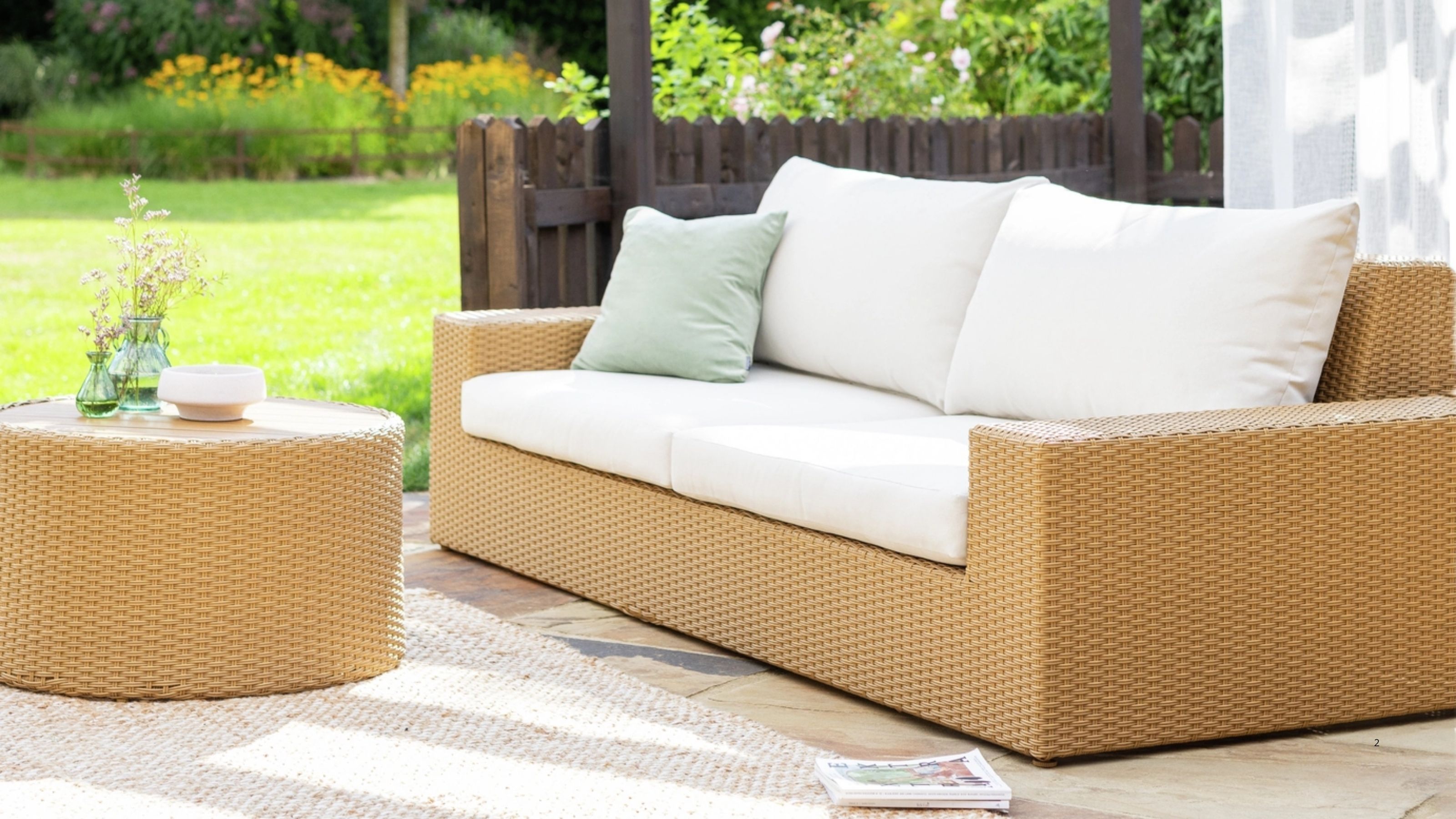 Image of a jute-effect outdoor sofa with white cushions and a matching coffee table on a sunny patio.