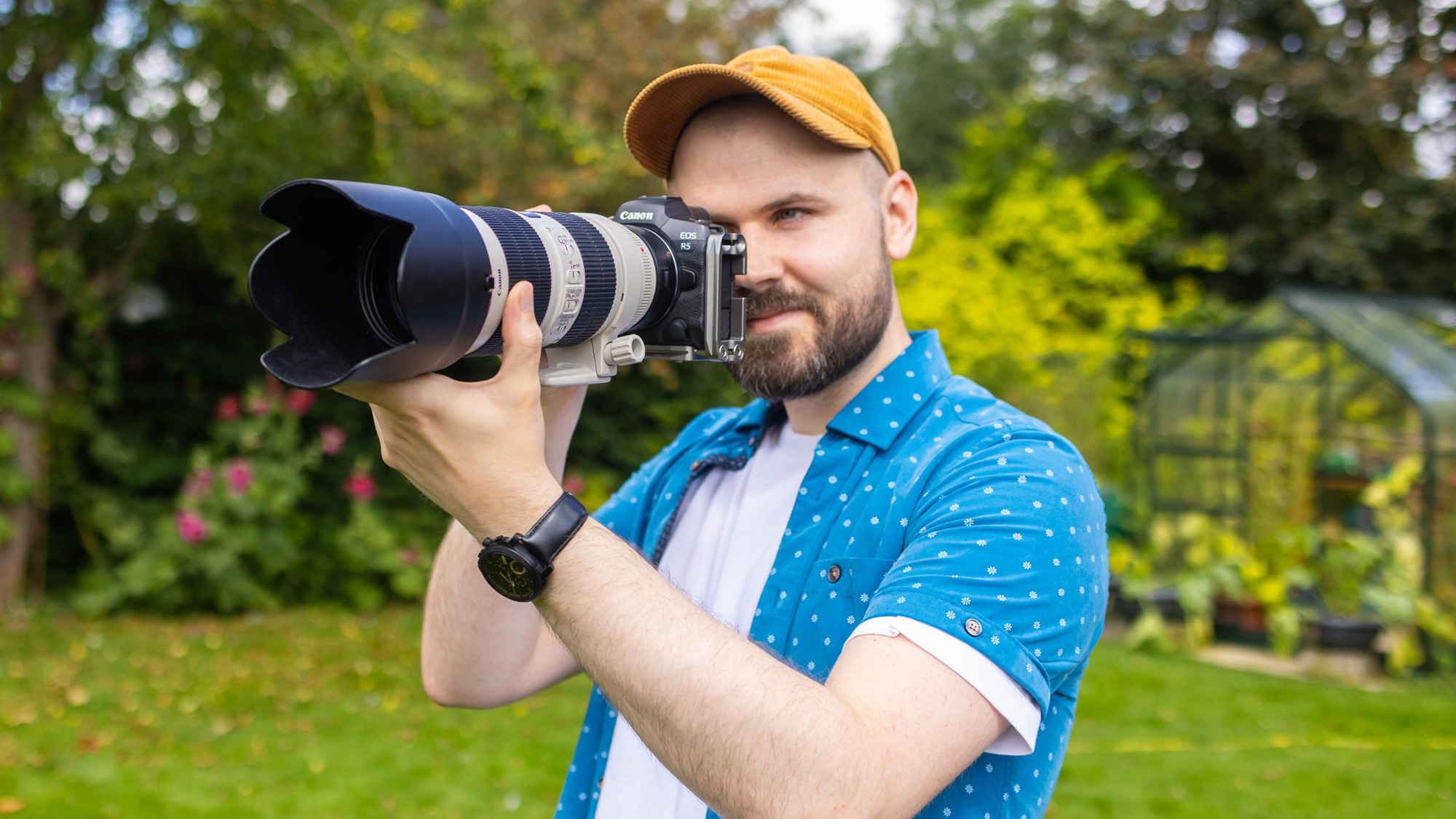 A man holding a Canon EOS R5 with an EF 70-200mm f/2.8 lens attached