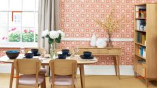 living room with coral patterned wallpaper on wall with a window behind a dining table to support expert advice to answer can you paint over wallpaper