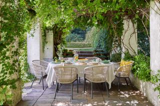 pergola covered in foliage over outdoor dining table