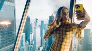 Sara Sampaio takes a selfie while a battle rages on behind her in Superman.