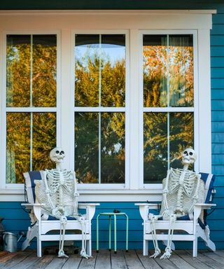 Skeletons sitting in chairs on porch for halloween