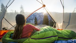 A woman watching sunrise from a tent