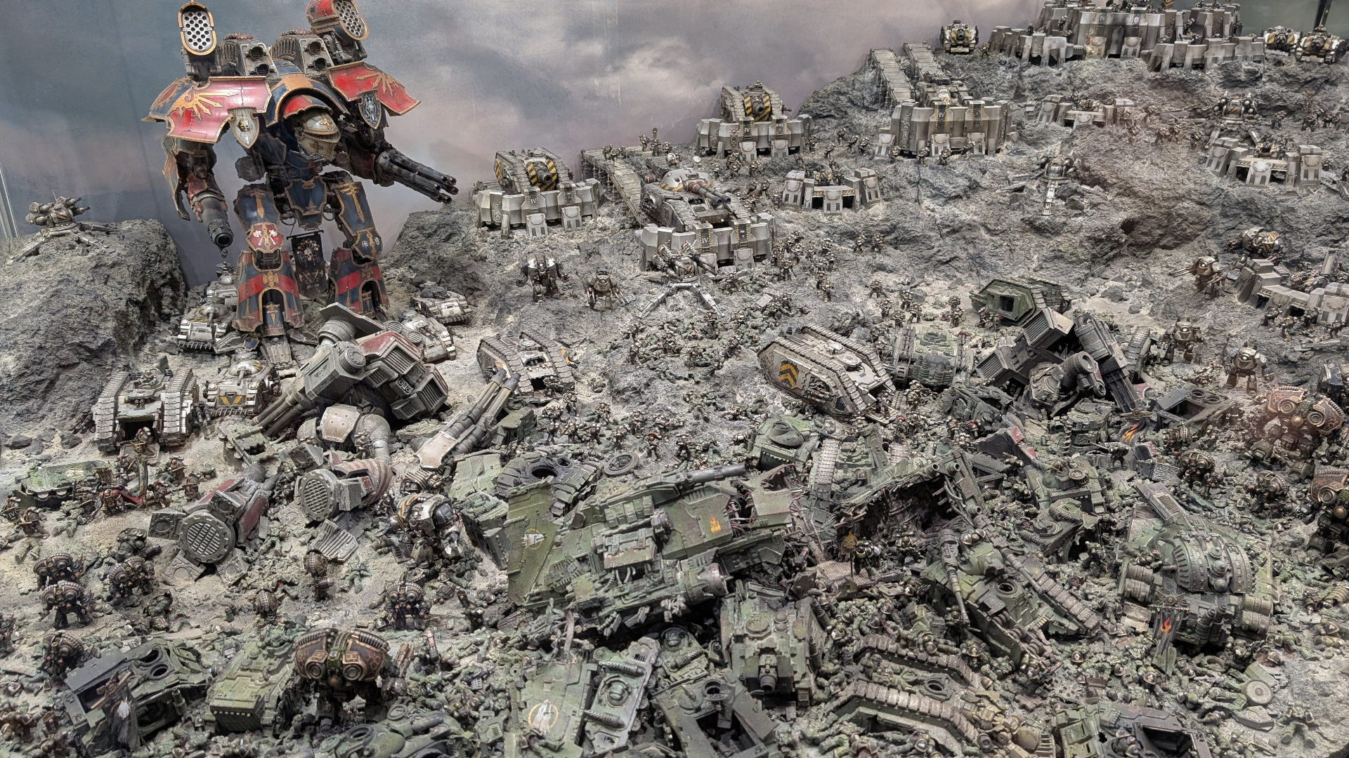 A Titan looms over a Warhammer 40,000 battlefield lined with tanks and gun emplacements