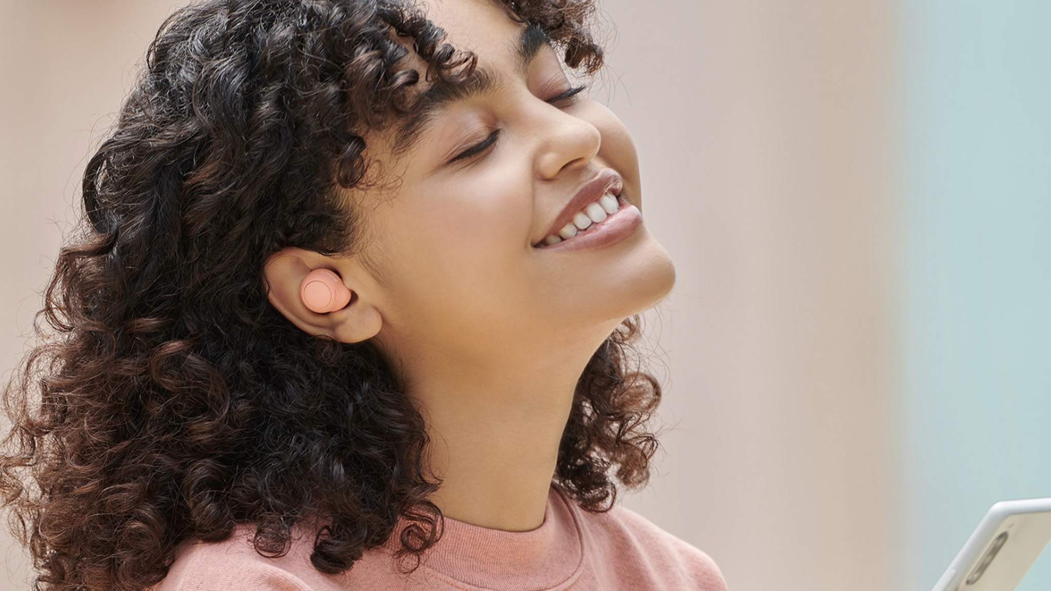 Lifestyle shot of pink Sony WF-C500 earbuds.